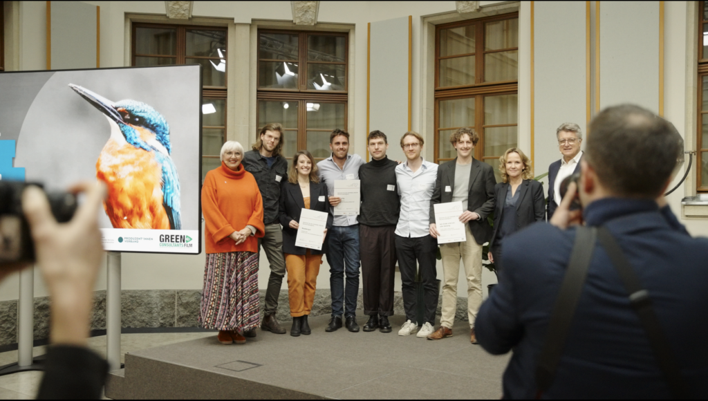 Schlussbild mit den Gewinner:innen auf der Bühne bei der Verleihung des Eisvogelpreis für nachhaltige Filmproduktionen im BMUV 2024