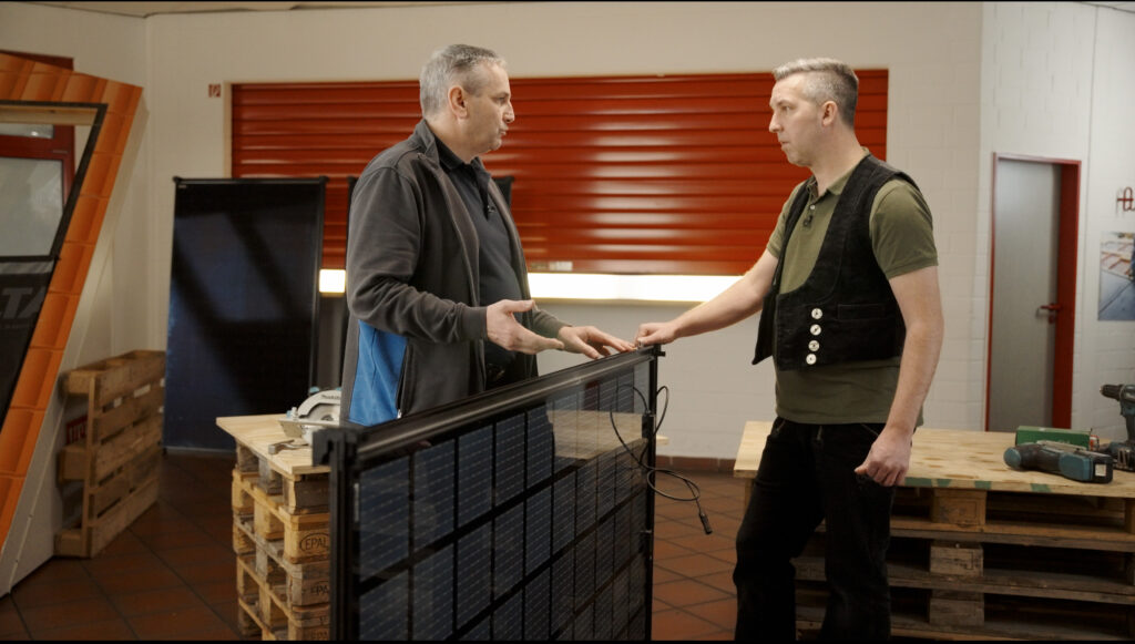 Die beiden Dachdecker besprechen vor der Kamera, wie die einzelnen Indach-Photovoltaik-Module angeschlossen werden. Sie stehen im Videostudio bei der Aufzeichnung eines Video Tutorials.