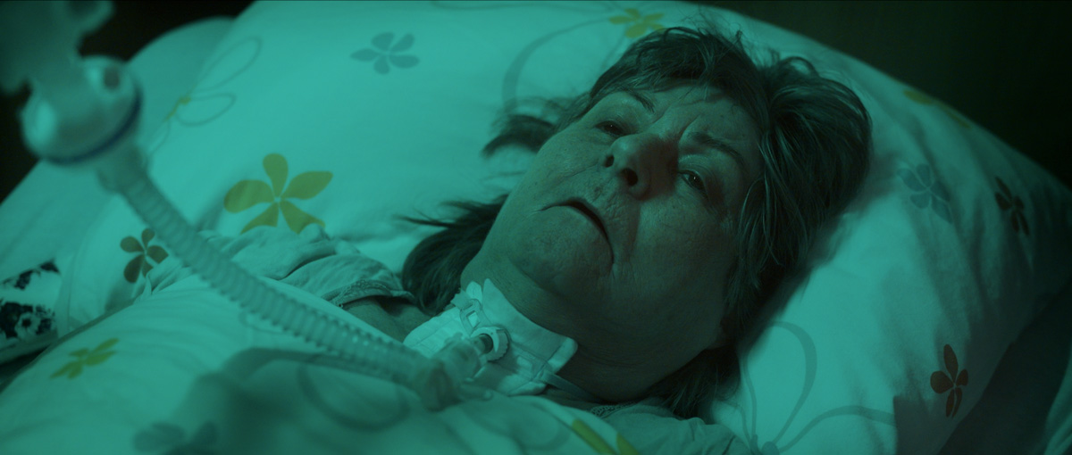 Patienten in der Pflege mit Beatmung im Krankenbett der Akademie Herzkreislauf bei grünlichem Licht, Standbild aus dem Pflege Imagefilm